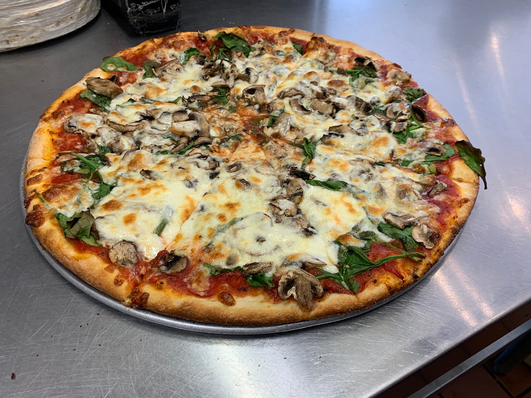Photo of a pizza with Spinage, mushroom, and cheese on it