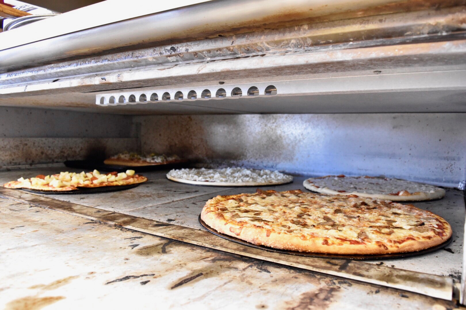 Photo of 5 diffrent large pizzas inside the oven